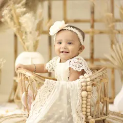 This little girl looks angelic in a white lace dress, seated in a wicker basket. Our boho theme is perfect for creating soft, delicate, and beautiful baby portraits.