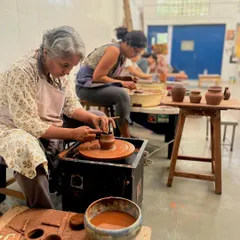 This is the beautiful energy of our studio. Students of all ages and backgrounds, deeply focused on their work, learning to trim their pieces on the wheel. It's a space for quiet concentration, shared learning, and the simple joy of making.