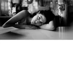 A candid black and white shot of Riya Miam resting at her table, conveying a sense of peace and introspection.