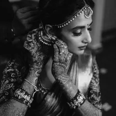 An intimate black and white shot of the bride getting ready. The focus on her hands adjusting her earring, with the intricate mehndi, creates a timeless and elegant image.