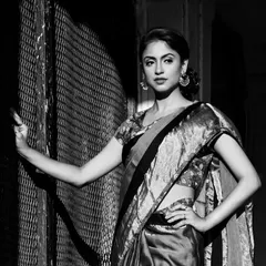 A cinematic black and white shot of a model in a traditional saree. The dramatic play of light and shadow gives this image a timeless, old-world feel.