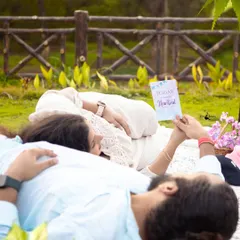A creative, relaxed pose during a picnic themed maternity shoot. This shot focuses on the details, like the card she is reading, which add a layer of personal storytelling to the session.