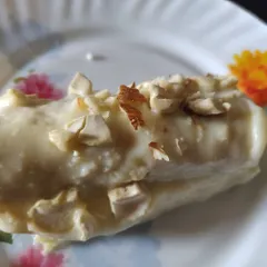 A single, tempting bread malai roll, showcasing the creamy texture and nutty topping.