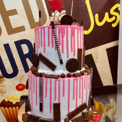 A 4kg two-tiered cake with a pink drip effect, overloaded with KitKats, Oreos, and other chocolate treats.