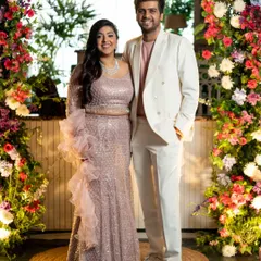 A stylish couple posing at their cocktail party, framed by beautiful floral arrangements. We cover all pre-wedding festivities.