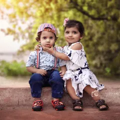 An adorable outdoor portrait of a brother and sister. The gentle interaction as she touches his chin makes for a truly special and authentic sibling photograph.