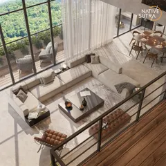 An aerial perspective of the open-plan living and dining area. This view emphasizes the spaciousness and flow we achieved, with a large sectional sofa anchoring the room and floor-to-ceiling windows connecting the interior to the lush green landscape outside.