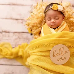 A sweet newborn nestled in a yellow wrap for a sunflower-themed shoot. One-month-olds can be tricky, but with experience, we can still get these beautiful, sleepy shots.