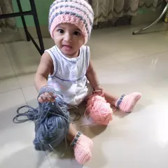 A playful moment with the yarn used for the Dewdrops beanie and booties set. It shows how soft and fun these handmade items can be for little ones.