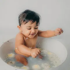 Playing with flower petals in the water, this little one is having the time of his life.