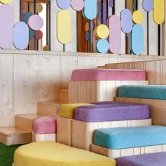 For the 'Nivriti' playschool, we designed this tiered seating area with colorful, soft cushions. The entire space was conceptualized from a toddler's perspective, with rounded corners, child-safe materials, and a playful color palette to create a stimulating environment.