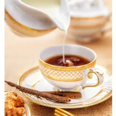 An elegant, high-key shot of milk being poured into a cup of tea, perfect for premium beverage brands or high-end hospitality advertising.