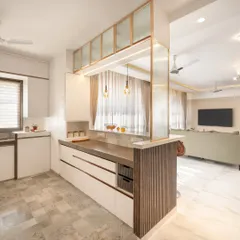 This open-plan kitchen features a breakfast counter that doubles as a partition to the living area. The design uses a mix of white cabinets, fluted glass, and patterned floor tiles for a bright and modern aesthetic.