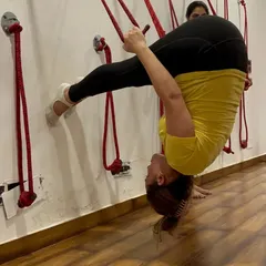 Our Yoga Teacher Training Course comes with job security. Here, a student practices an advanced inversion using the rope wall.