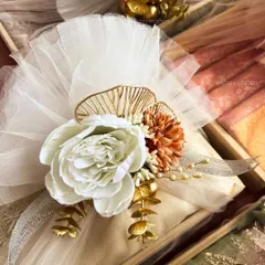 A different color palette for trousseau styling, featuring a large white peony and warm-toned flowers against white tulle. Every design is customized to the client's wedding theme.