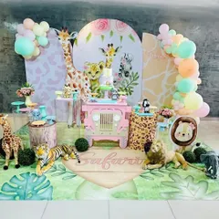 A full view of our pastel safari theme, perfect for a baby girl. The setup features a pink jeep-shaped dessert table, adorable animal characters with floral accents, and a custom printed floor mat.