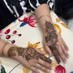 A simple and elegant Arabic design. Each hand has a single trail of henna, one with a floral motif and the other with a swirling paisley, perfect for a minimalist look.