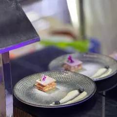A deconstructed dessert masterpiece. This layered pastry is presented with artistic swipes of cream and carefully placed berries, turning a sweet treat into a piece of edible art.
