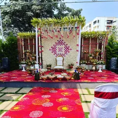 The same elegant Seemantham stage, providing a full view of the colorful printed carpet and the lush green surroundings of the venue.