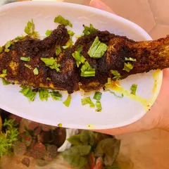 A perfectly fried river fish, crispy on the outside and soft on the inside, garnished with fresh herbs.
