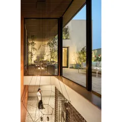 This double-height volume, clad in rich Burma teak, acts as a luxurious transition to the private executive suite. The soaring space is graced by a minimal chandelier and offers a glimpse of the terrace garden.