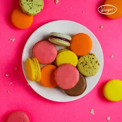 A colourful plate of our assorted macarons. The bright pink background highlights the beautiful colours of these delightful French confections.