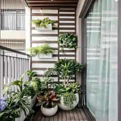 This balcony showcases a clean, contemporary look with a mix of large and small planters. The white and brown color scheme for the planters and wall panels creates a cohesive design that makes the greenery pop.