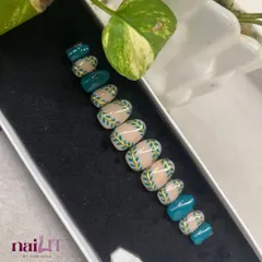 A beautiful set of custom press-on nails featuring a teal and nude design with hand-painted leaves and gold accents. Perfect for a traditional or festive look.