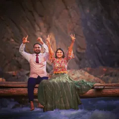 A fun and energetic shot of a couple on a wooden bridge over a flowing river, showing their playful side.