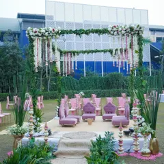 For a fresh and romantic daytime wedding, I designed this garden mandap using a vibrant pink and green palette. The structure is covered in greenery, with hanging floral strings of rajnigandha and roses, and traditional bells for a touch of South Indian charm.