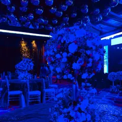 A view from the dance floor of a high-energy sangeet. The ceiling is covered in mirror disco balls, reflecting the deep blue ambient lighting and setting the perfect mood for a rave-themed party.