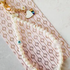 I love making your stories into something you can carry every day. This custom phone charm was made with love, featuring the owner's initial 'T', her daughter's initial 'R', a rainbow heart, and a protective evil eye, all tied together with elegant pearls.