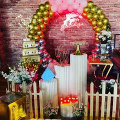 A beautiful setup against a brick wall, showing how I can work with existing venue features. The decor includes a circular balloon arch, a neon sign, and elegant plinths.