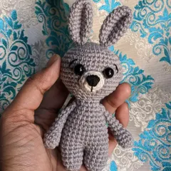 The little grey bunny keychain against a patterned background.