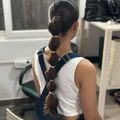 A bubble ponytail created with simple elastics for a more casual, playful look. This style adds texture and volume to a standard ponytail, making it great for daytime events or shoots.