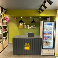 The reception and billing counter inside the FnP store. The design incorporates the brand's logo and colors, with a fluted panel counter and functional placement of essentials like the refrigerated display.