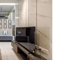 A view of a modern entertainment unit against a white marble-paneled wall. This image showcases the sleek, minimalist design and the effective use of materials in the space.