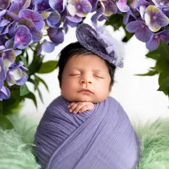A detailed close up of a sleeping newborn's face, framed by purple flowers and wearing a delicate little hat. These shots are perfect for capturing those tiny features you never want to forget.