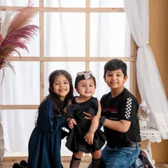 A lovely portrait of three siblings together. The older brother and sister protectively hold their baby sister, showcasing the beautiful dynamic in a larger family.