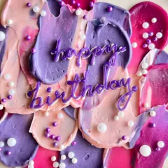 A close-up of my abstract buttercream art. I use a palette knife to create textured strokes in shades of pink, purple, and fuchsia, topped with delicate sugar pearls for a modern, artistic birthday cake.