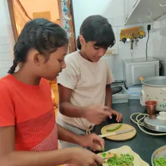 Two older girls collaborate in the kitchen, preparing a nutritious meal for the street dogs who visit our school. This act of service combines practical cooking skills with empathy and care for our community animals.
