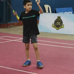 The focus and determination of a young athlete preparing to serve during a competitive match. We create a professional tournament environment where junior players can test their skills and grow.