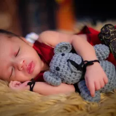 Even the tiniest wizards need their sleep. This newborn is dreaming of magical adventures, cuddled up with a teddy bear and holding a miniature wand.