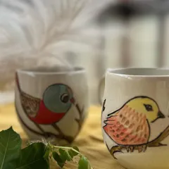Another detail shot of the hand-painted bird mugs, showing the delicate brushwork and vibrant colors.