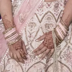 A detailed view of the fine threadwork on the lehenga skirt. The combination of pink and gold threads creates a subtle yet rich texture.