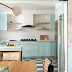 The kitchen from the Aqua Home continues the home's coastal theme with crisp duck egg blue cabinets. A sliding glass partition separates it from the dining area, offering flexibility while maintaining a light, open feel.