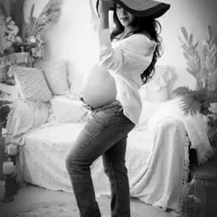 A chic and casual black and white portrait. The mom-to-be, wearing jeans and a white shirt, looks stylish and confident in this modern take on maternity photography.