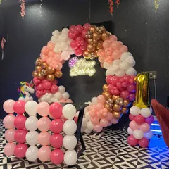 A full view of the unicorn-themed birthday decoration, featuring a large balloon ring with a 'Happy Birthday' sign, perfect for photos. The color palette includes rose gold, pink, and white balloons.