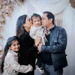 Kisses for the little one! This family portrait was taken in our studio against a beautiful floral arch, showing how we can create celebratory setups.