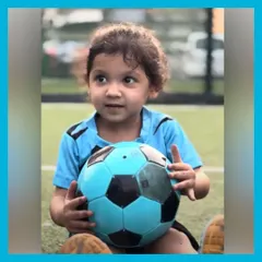 This little player is holding her ball, ready for the next fun activity. Her curious and happy expression captures the spirit of our toddler football classes.